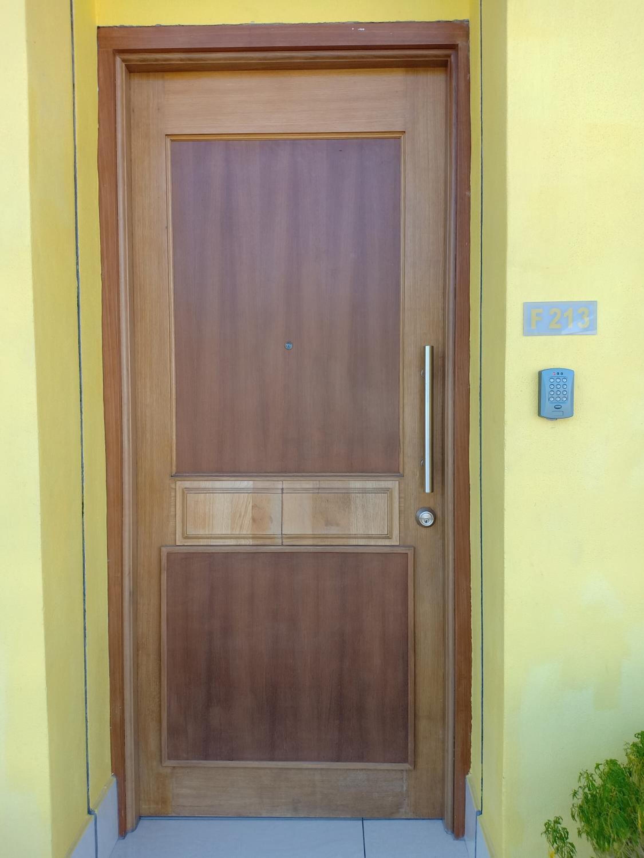 A wooden door with a handle and a keypad lock.