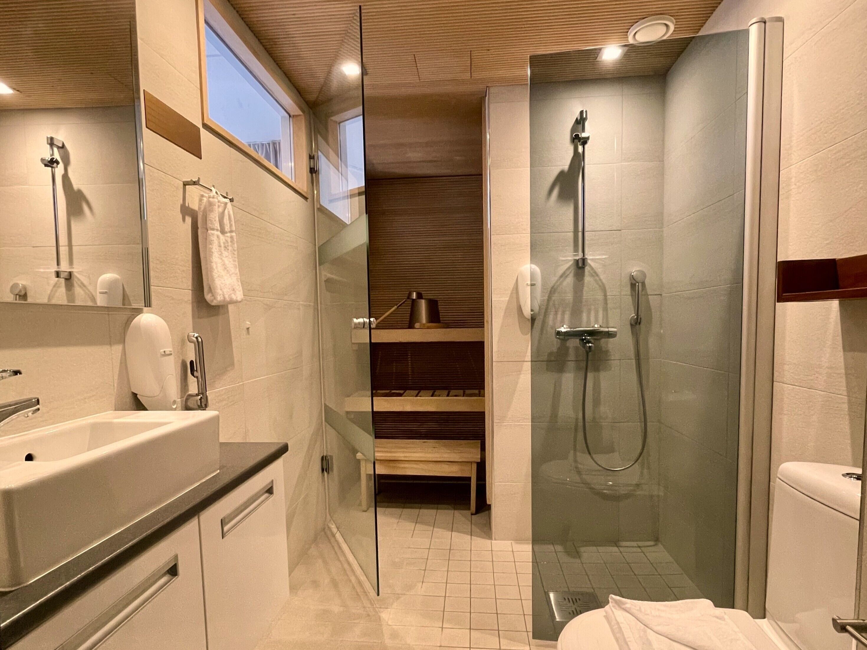 Une salle de bain moderne avec une douche à parois de verre, un lavabo avec un miroir et un porte-serviettes.