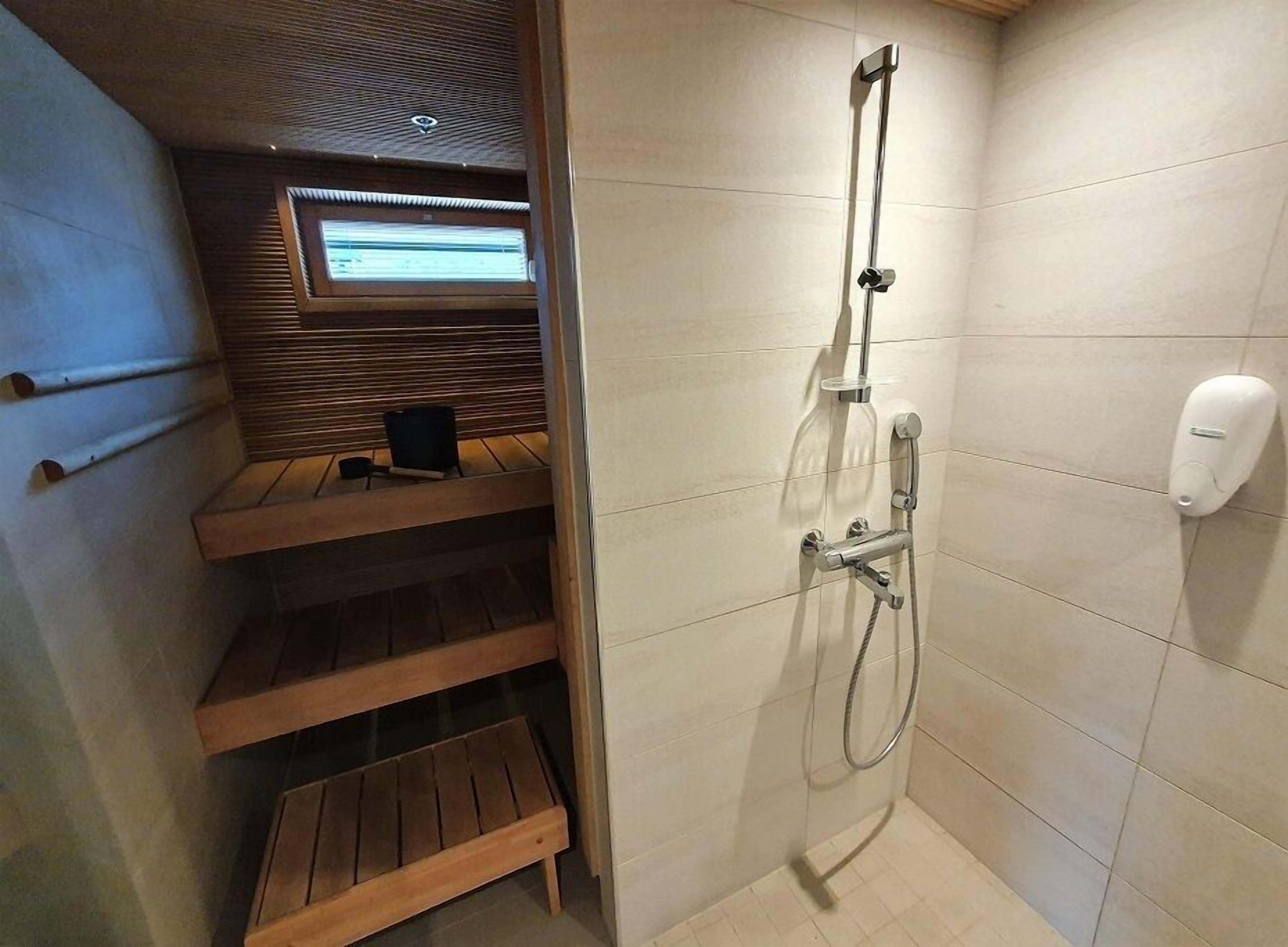 Une salle de bain avec une douche, des toilettes et une étagère sur laquelle se trouve une chaise.