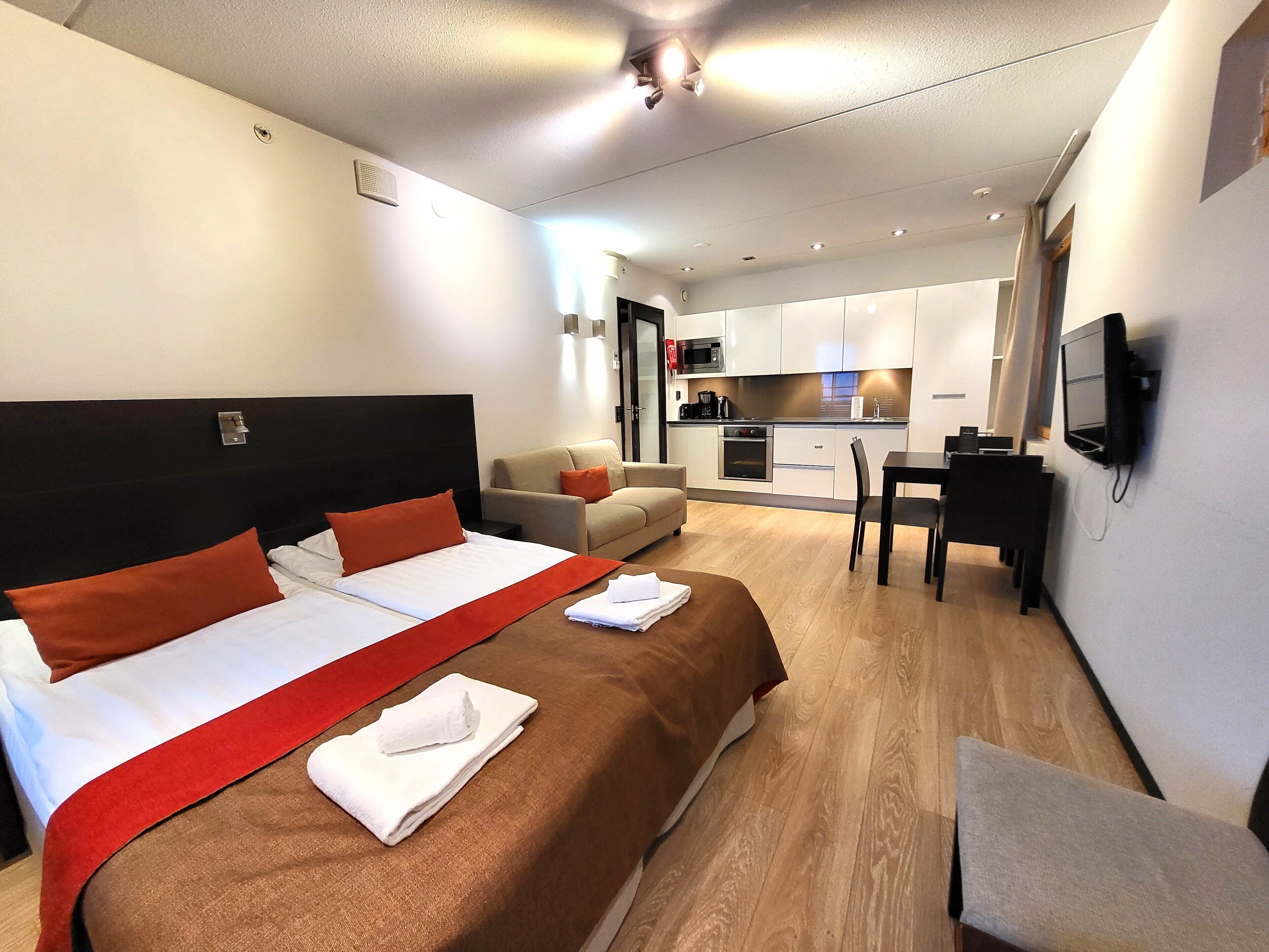 Una habitación de hotel con cama, sofá, mesa de comedor y kitchenette.