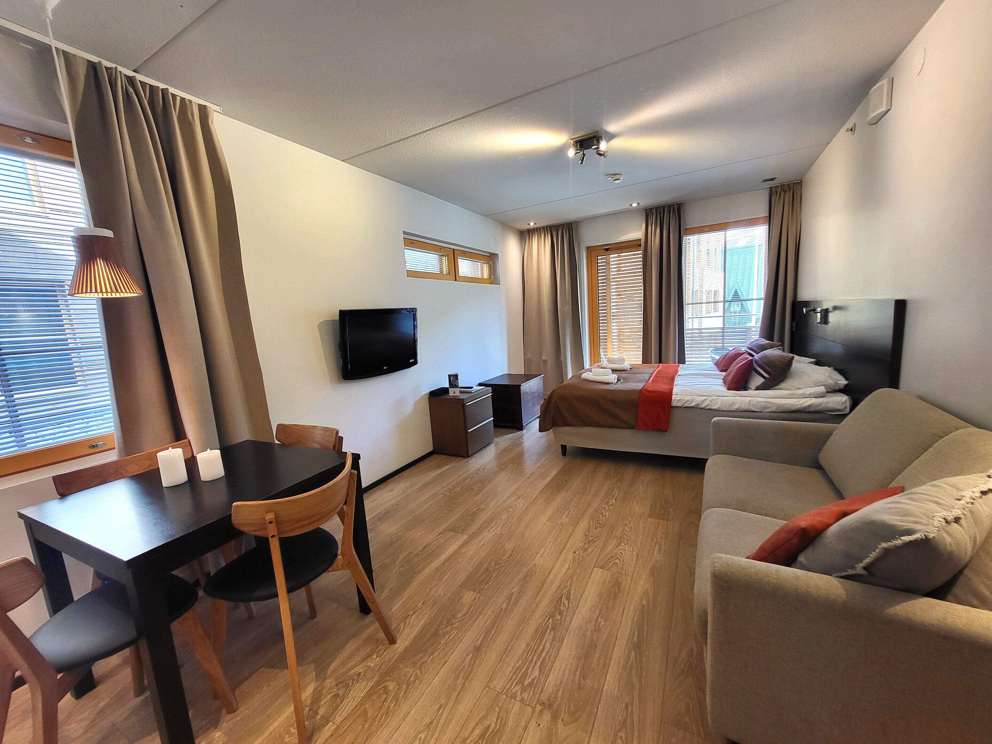 Une chambre d’hôtel avec un lit, un canapé, une télévision, un bureau et une chaise.