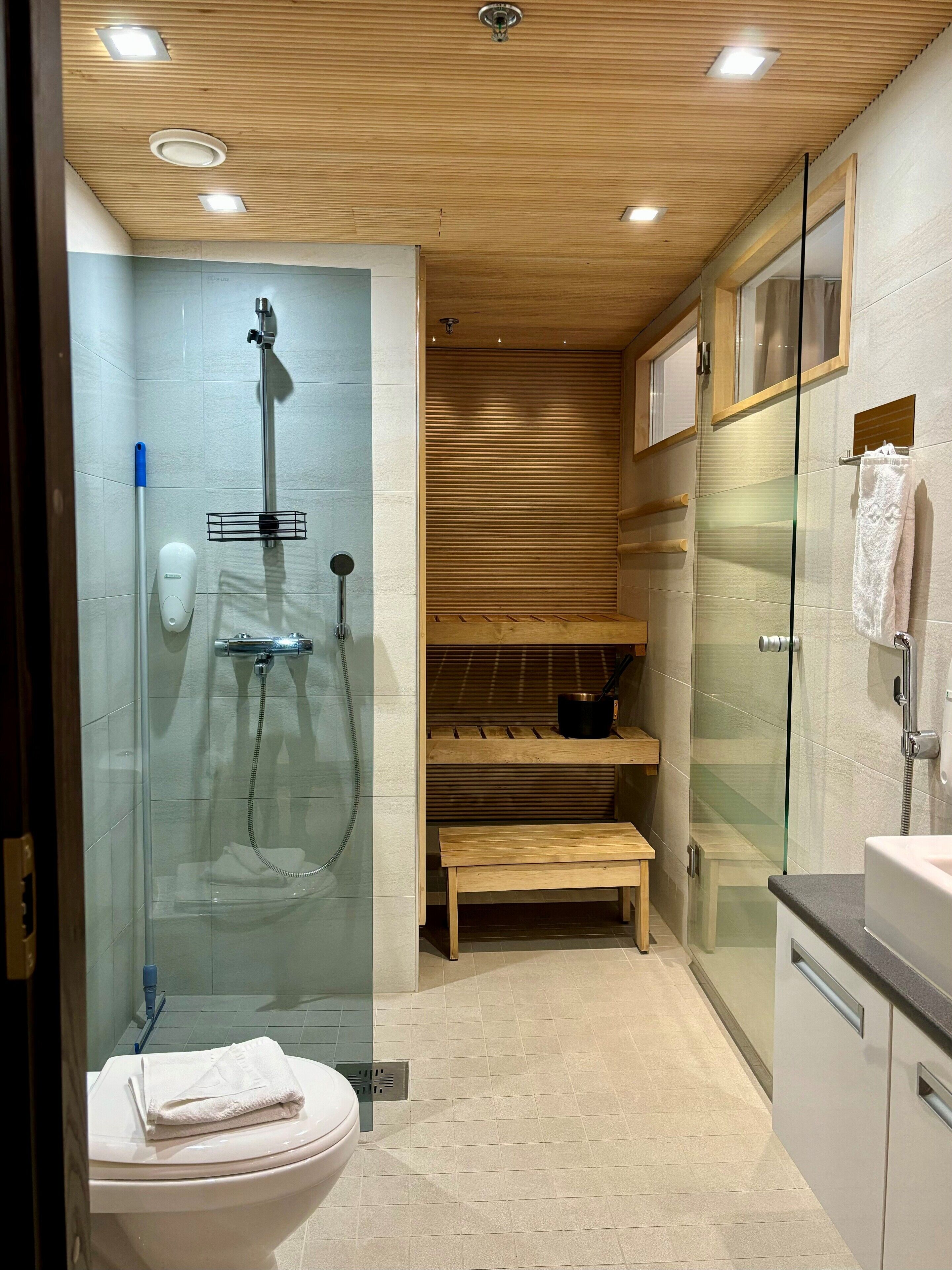 Un baño moderno con ducha envuelta en vidrio, inodoro y tocador con lavamanos.