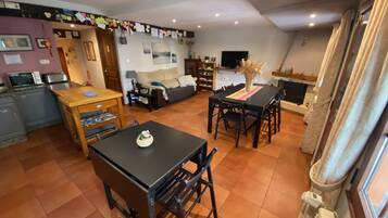 A spacious living area with a dining table, sofa, and kitchen area.