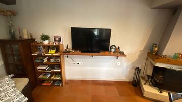 A living room with a flat-screen TV mounted on a wooden shelf, a fireplace, and a bookshelf filled with books.