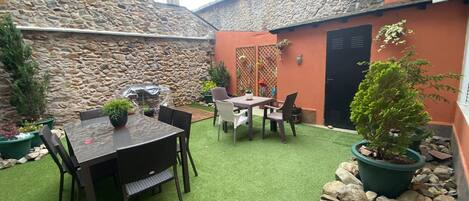A patio with a stone wall, a wooden table, and chairs.
