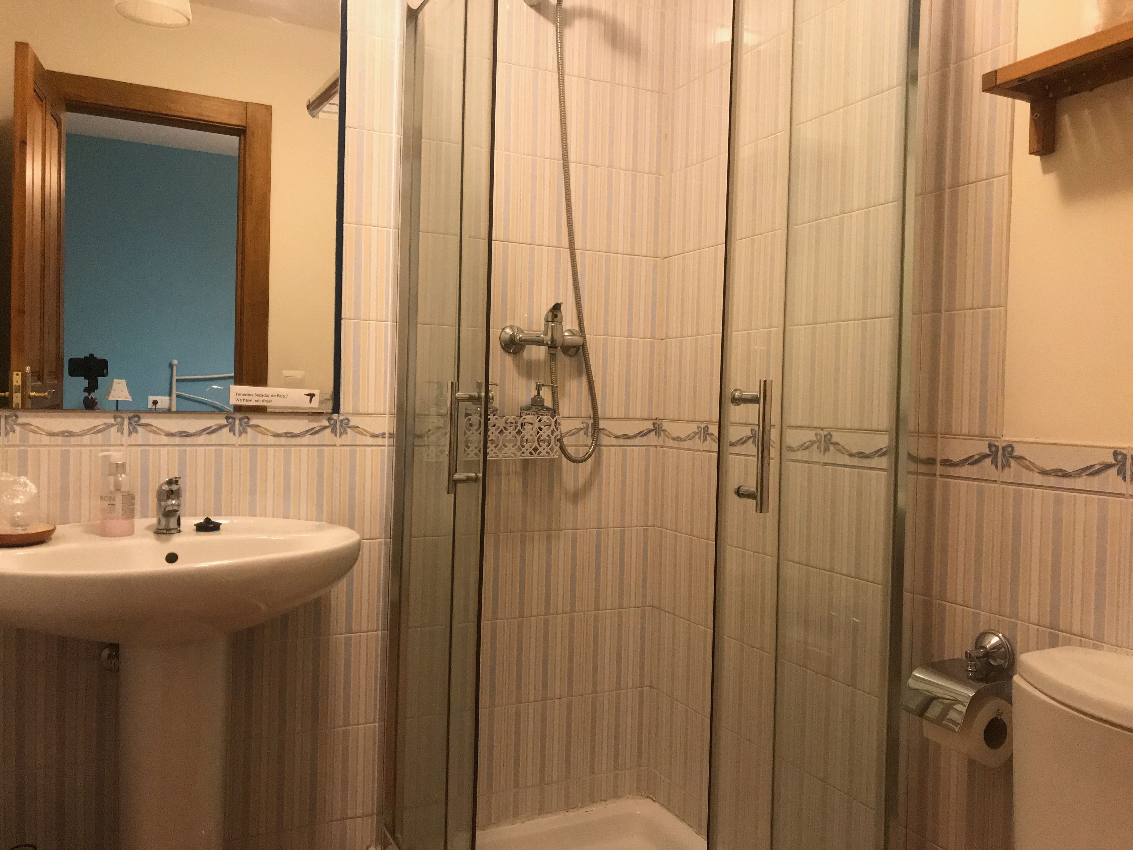 A bathroom with a glass-enclosed shower, a sink, and a toilet.