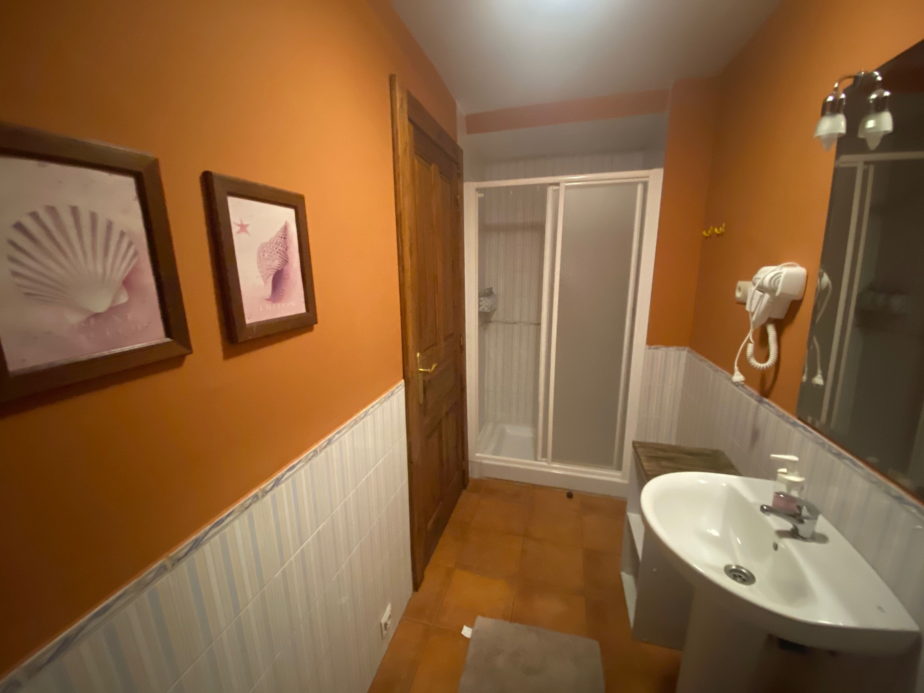 Een badkamer met een wastafel, spiegel en foto's in een lijst aan de muur.