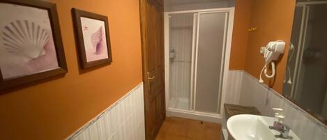 Un baño con lavamanos, espejo y cuadros en la pared.