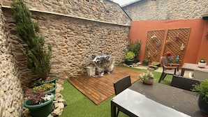 Un muro de piedra, una mesa de madera y macetas con plantas en un patio.
