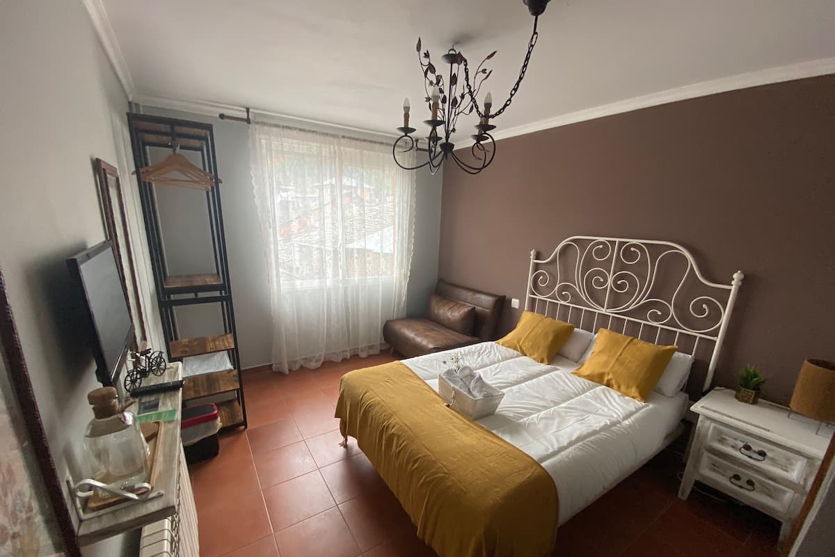 Un dormitorio con cama, mesita de noche, cómoda, espejo y candelabro.