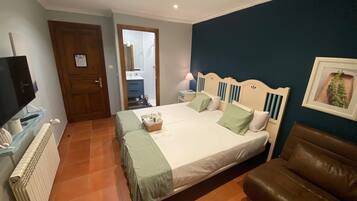 A bedroom with a bed, a television, a dresser, a brown leather chair, and a blue wall.