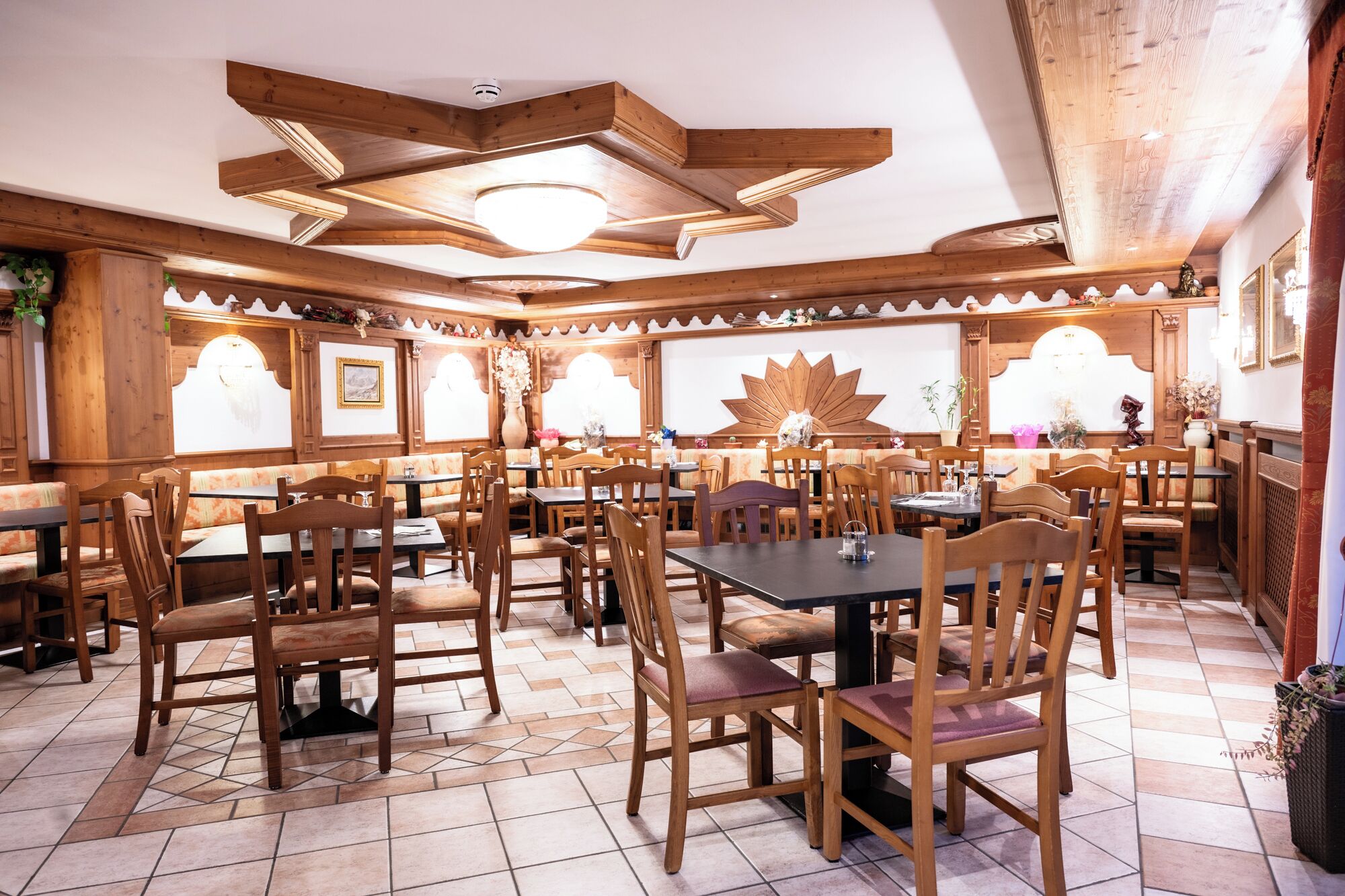 Un restaurante con mobiliario de madera, suelo de baldosas y un techo alto con vigas a la vista.