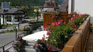 A balcony with a wooden railing, potted plants, and a white tablecloth. - Hotel Orchidea (Vermiglio)