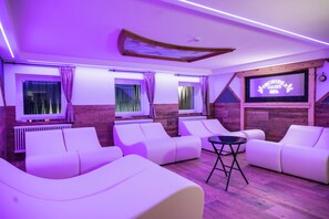 Ein Zimmer mit weißen Sofas, einem kleinen Tisch und einem Bildschirm, der 'Orchidede Oasis Spa' anzeigt.