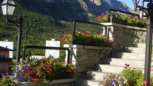 A set of stone steps with flower planters, a metal railing, and two street lamps. - Hotel Orchidea (Vermiglio)
