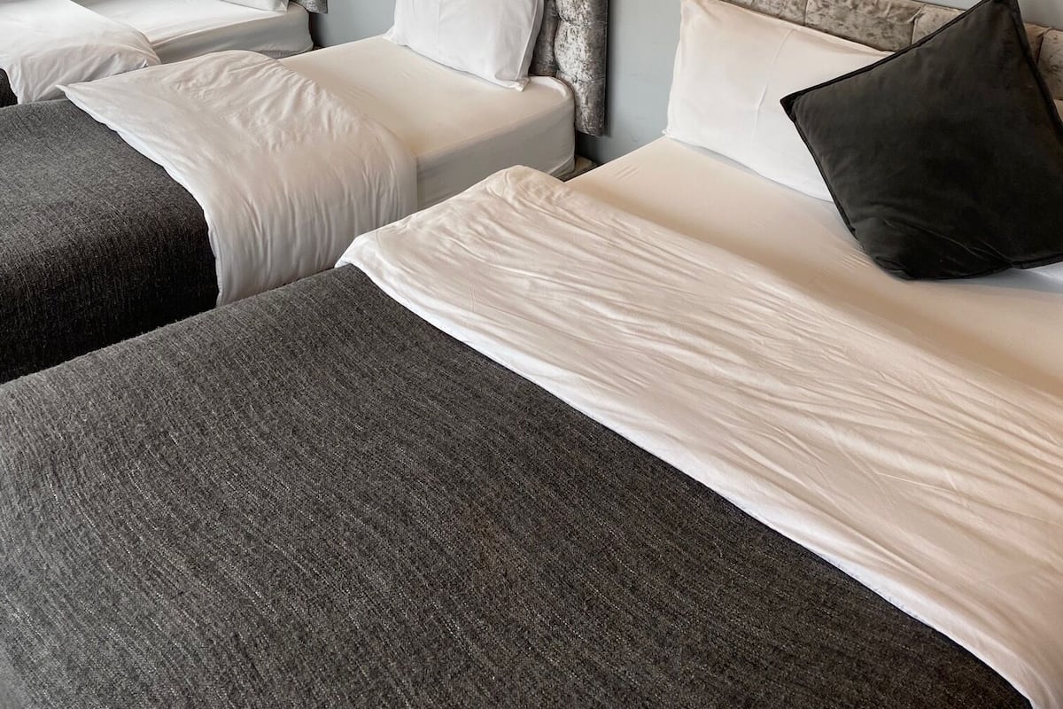 A hotel room with two beds, each with a headboard and pillows. There is a window providing natural light.
