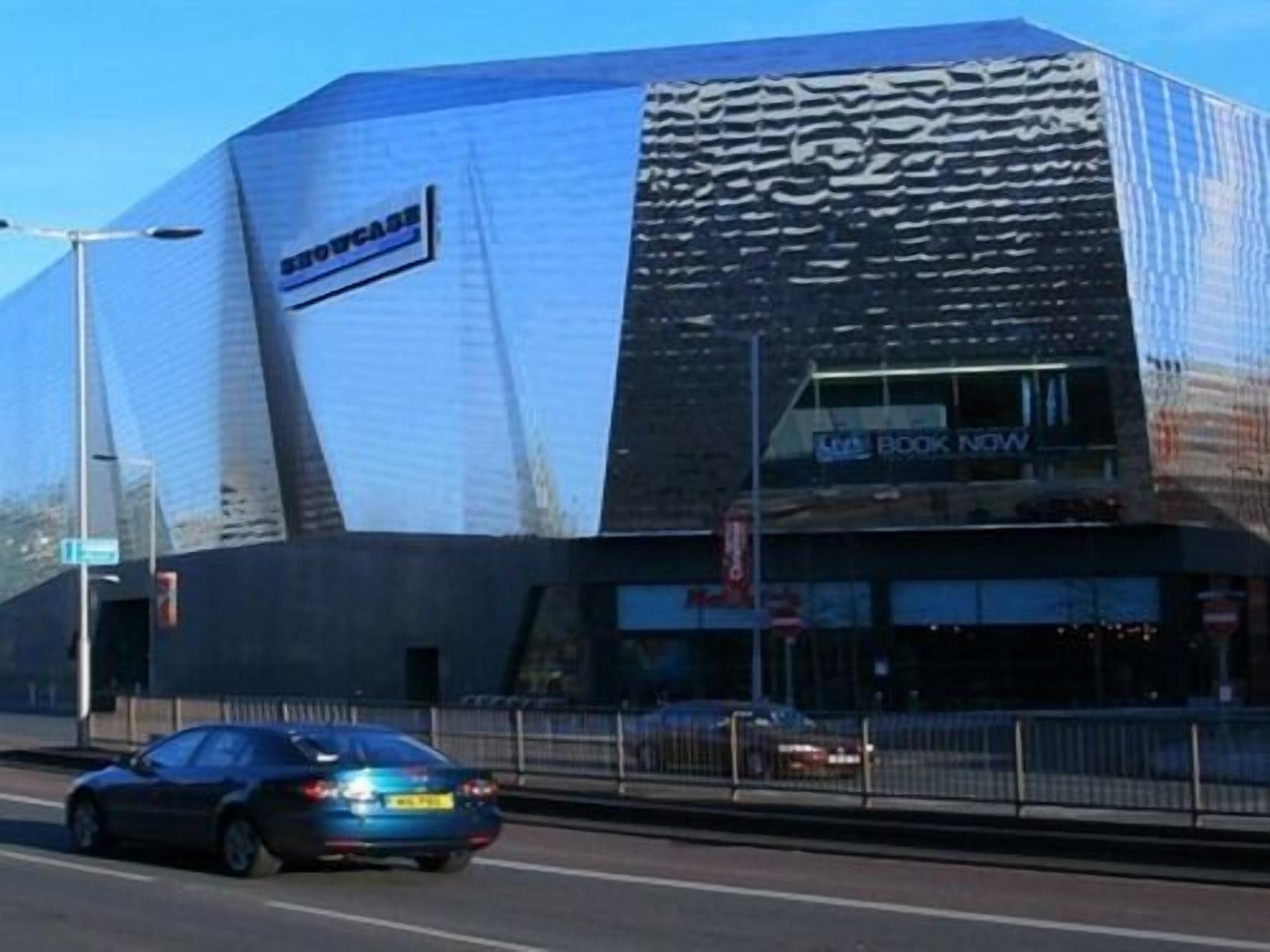 Un edificio moderno con fachada reflectante y un letrero que dice 'Book Now'.