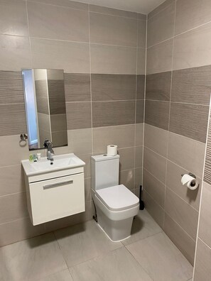 A modern bathroom with a white sink, mirror, and toilet.
