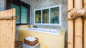 Un baño con bañera, ventana y valla de bambú.
