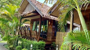 Una casa de madera con techo de paja, rodeada de exuberante vegetación tropical.