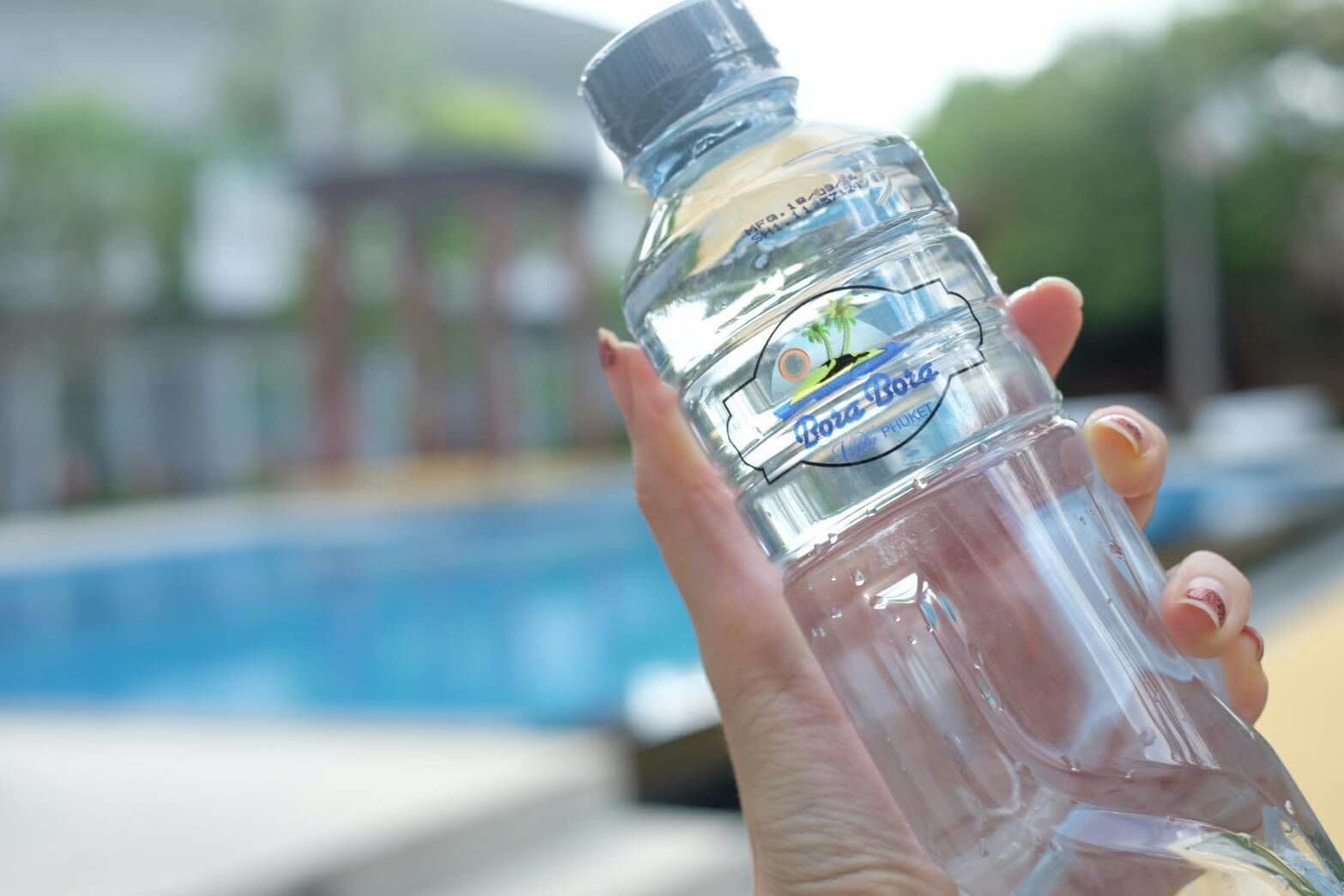 Een doorzichtige plastic fles met een etiket waarop 'Bora Bora Phuket' staat, vastgehouden door een hand.