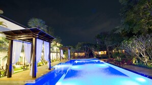A nighttime swimming pool area with a covered seating area and a well-lit pool. - Bora Bora Villa Phuket (Chalong)