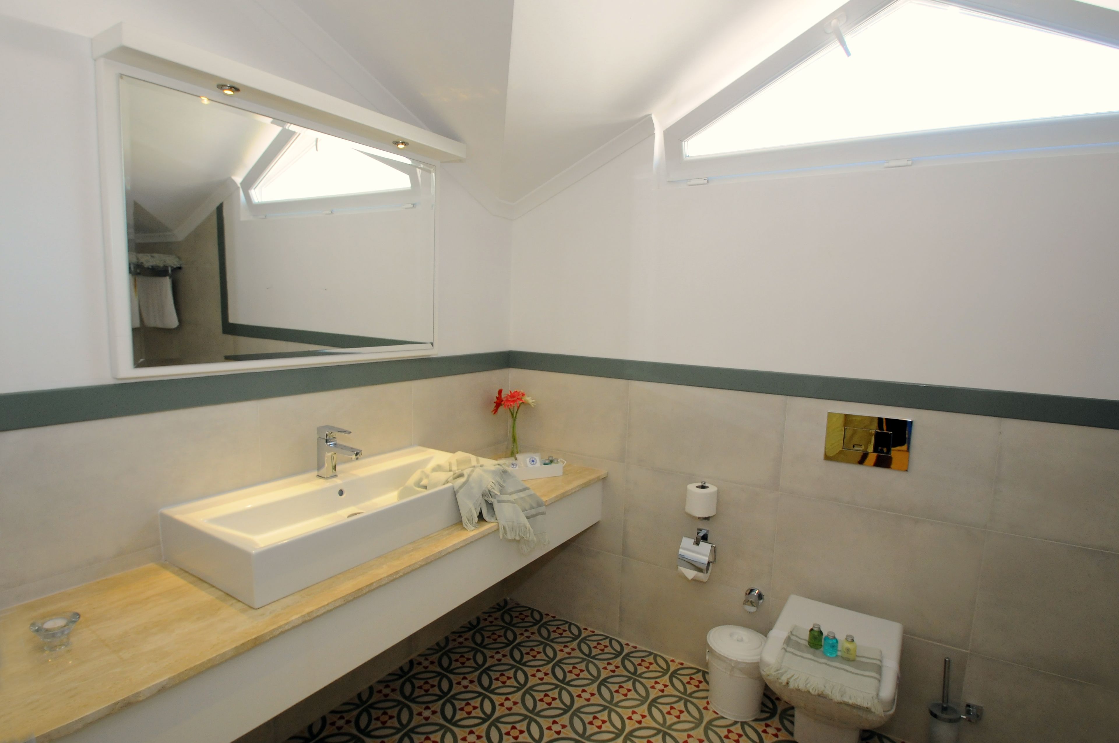 A modern bathroom with a large sink, mirror, and a patterned floor.