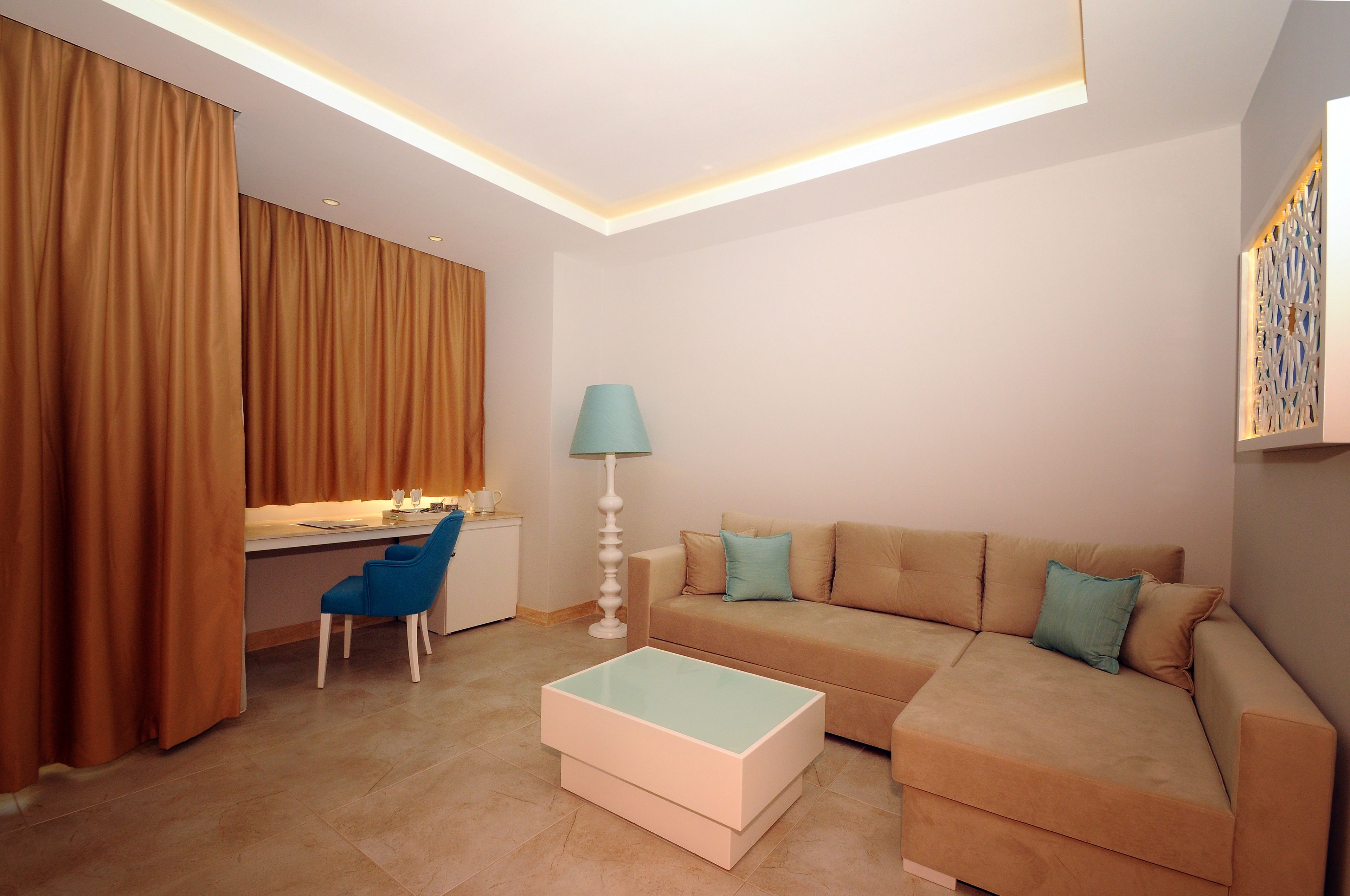A modern living room with a sofa, a coffee table, a desk with a chair, and a lamp.