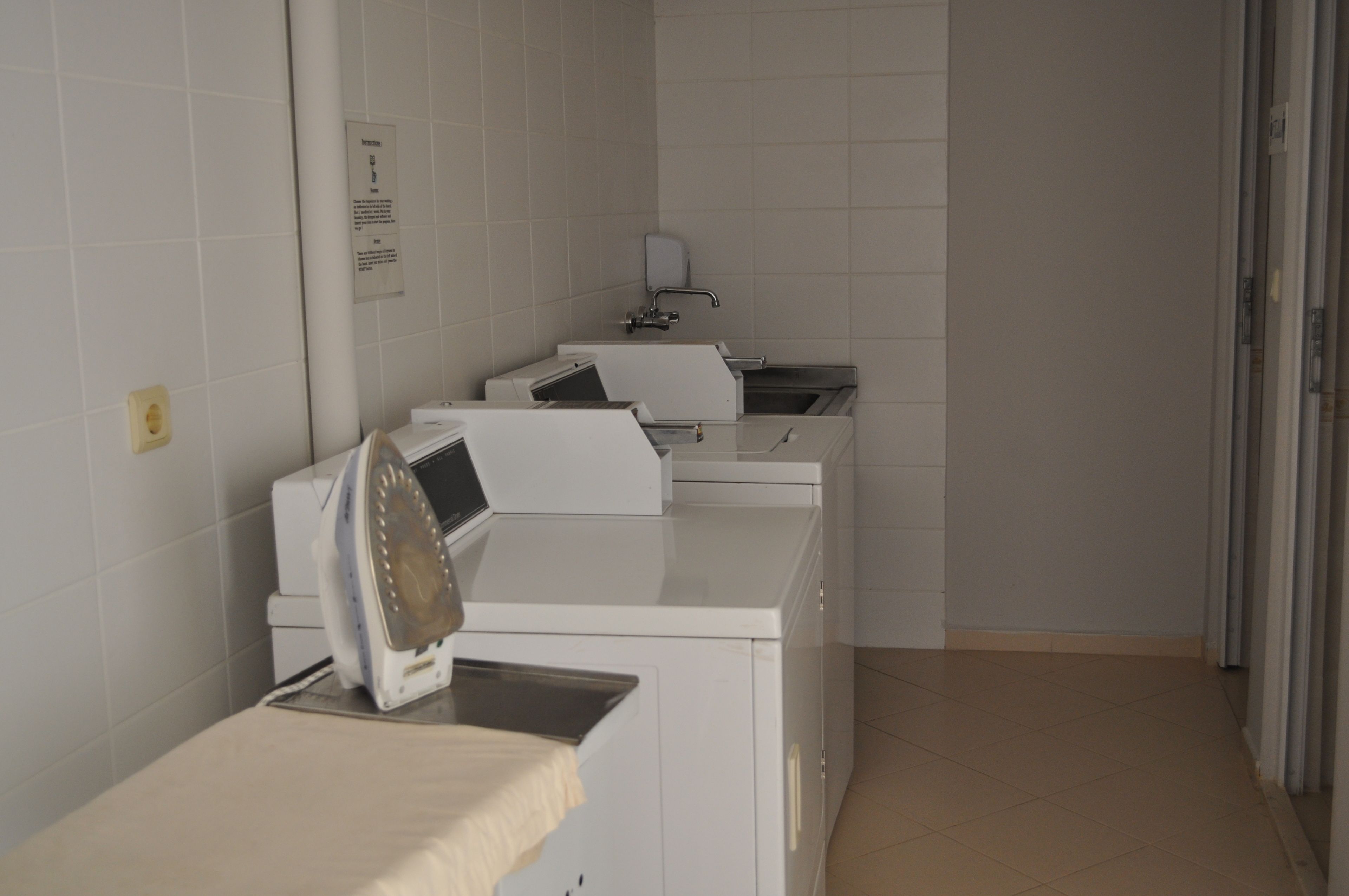 A laundry room with multiple washing machines and a sink.