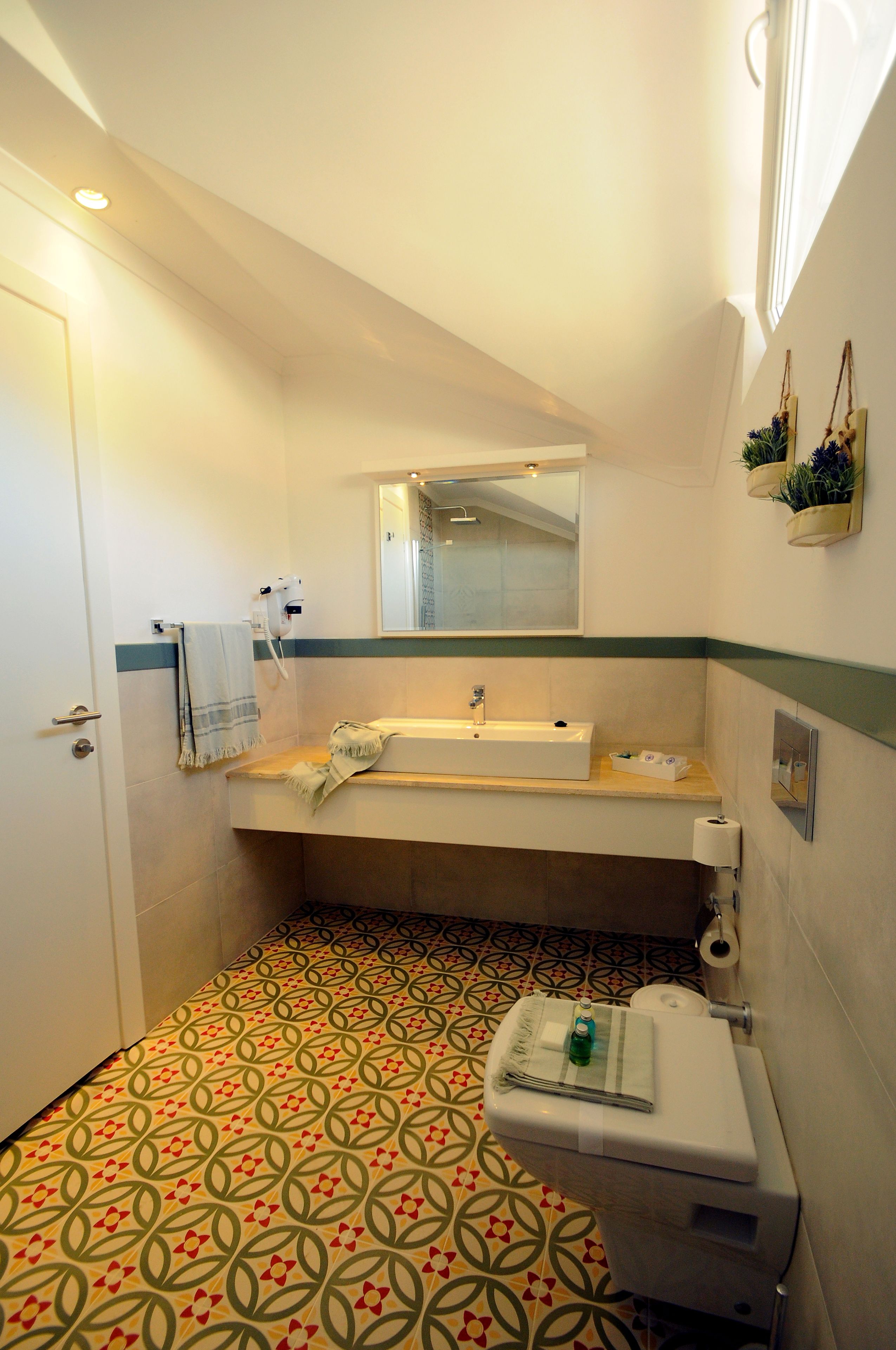 Une salle de bain avec un carrelage décoratif, un lavabo, des toilettes et un miroir.