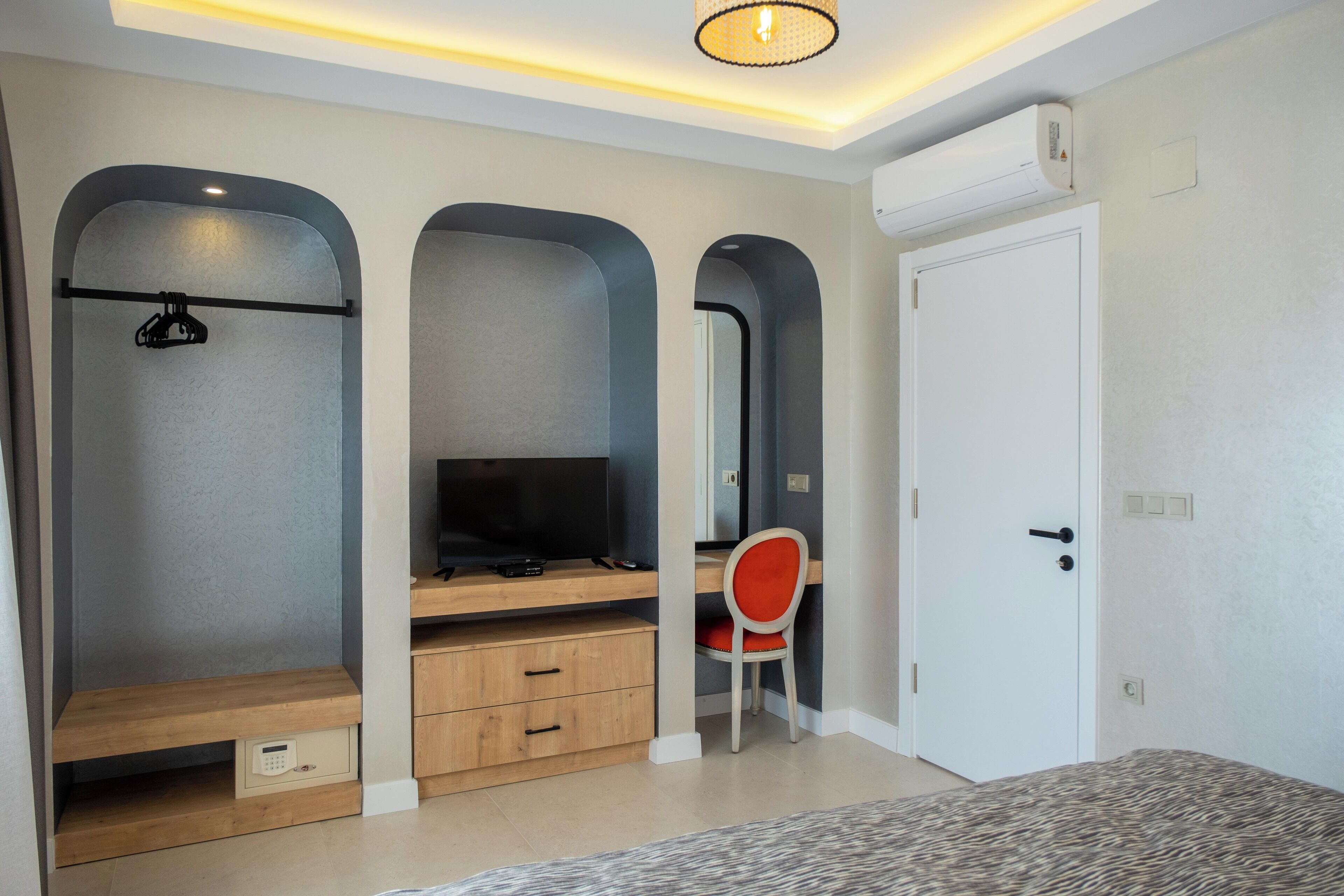 A bedroom with a bed, a desk with a chair, a TV, and a wardrobe.