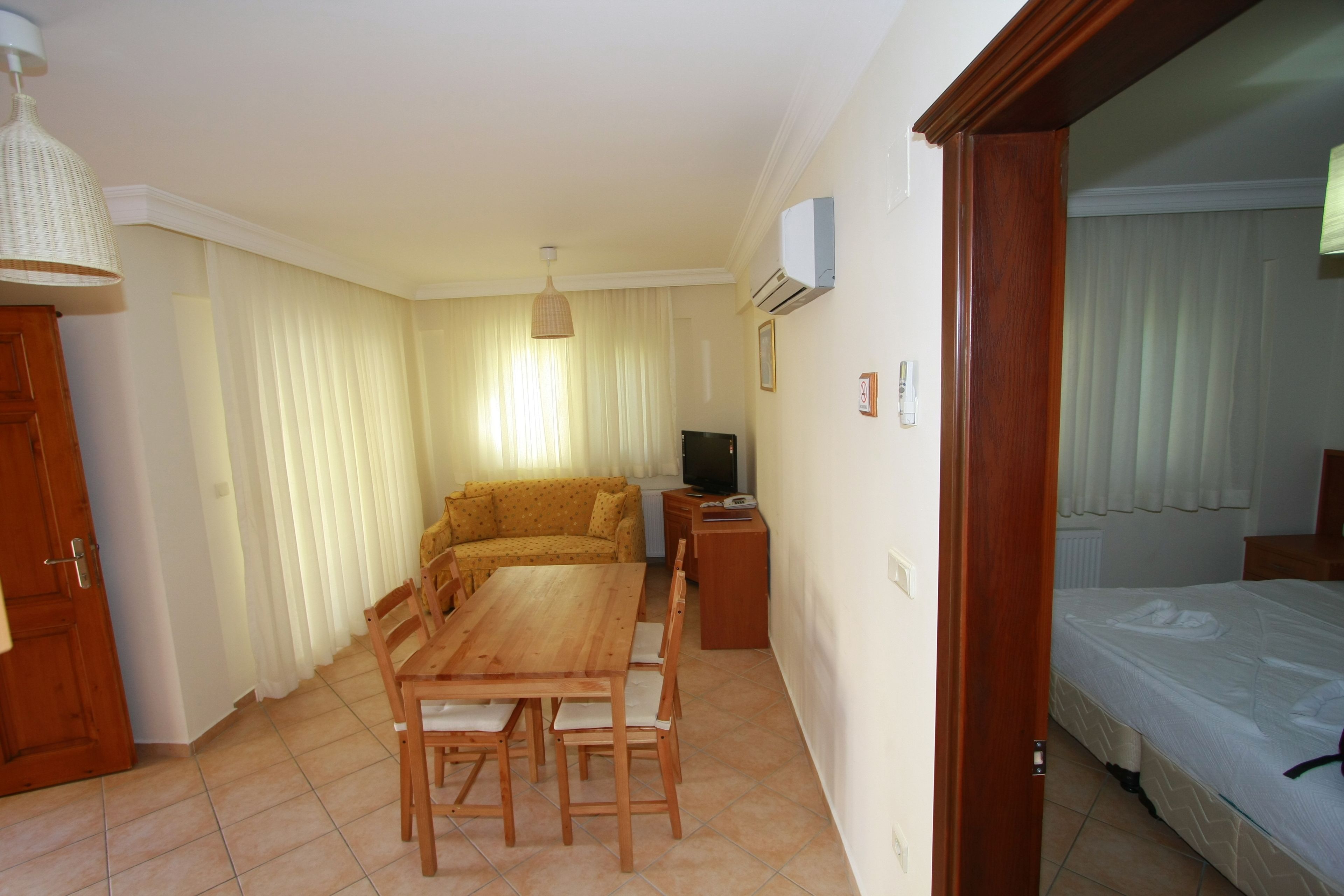 A compact living space with a dining area, sofa, TV, and a bed.