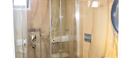 A bathroom with a glass-enclosed shower, a toilet, and a sink.