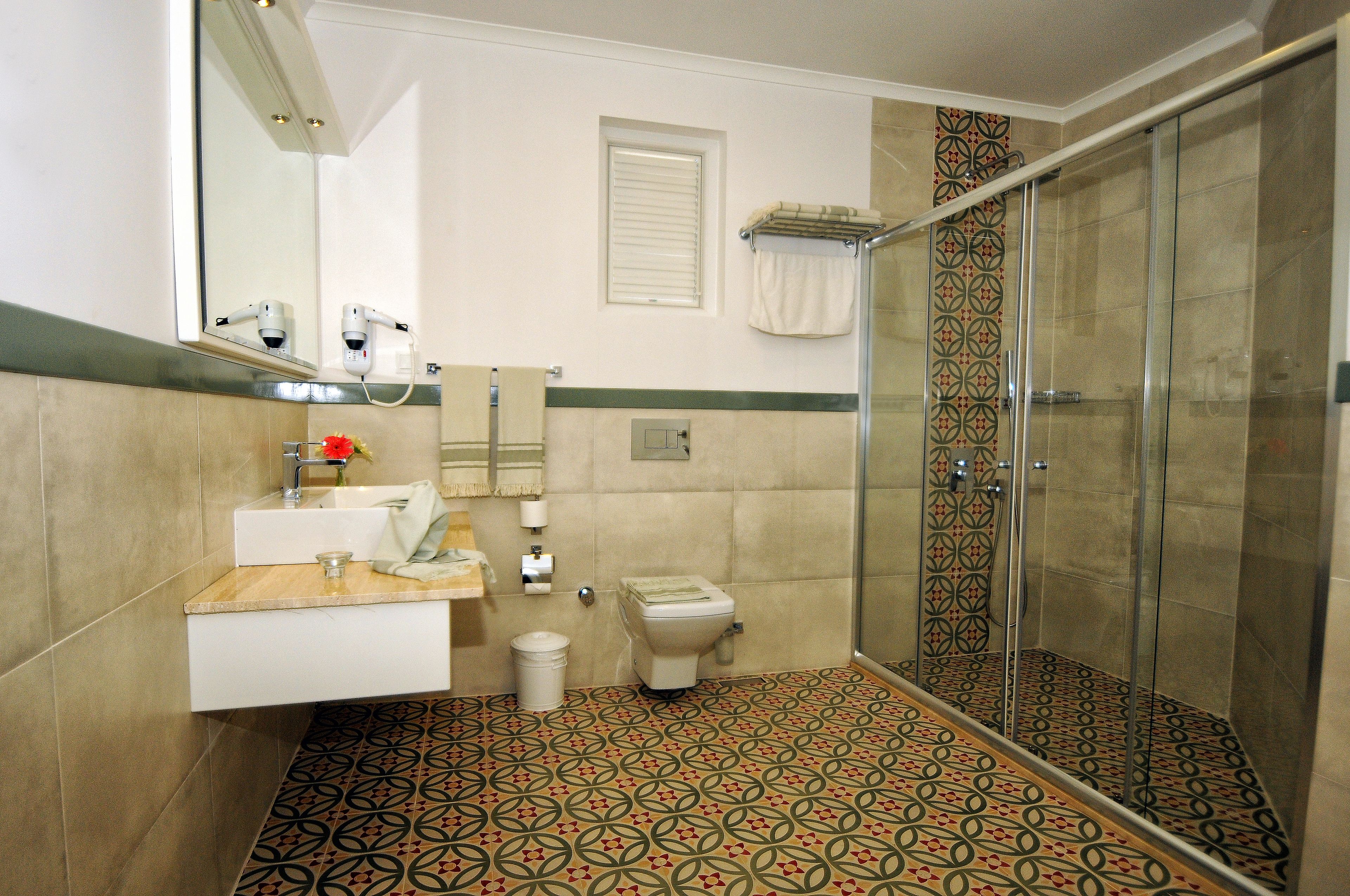 Ein Badezimmer mit Dusche, Toilette, Waschbecken und Spiegel.