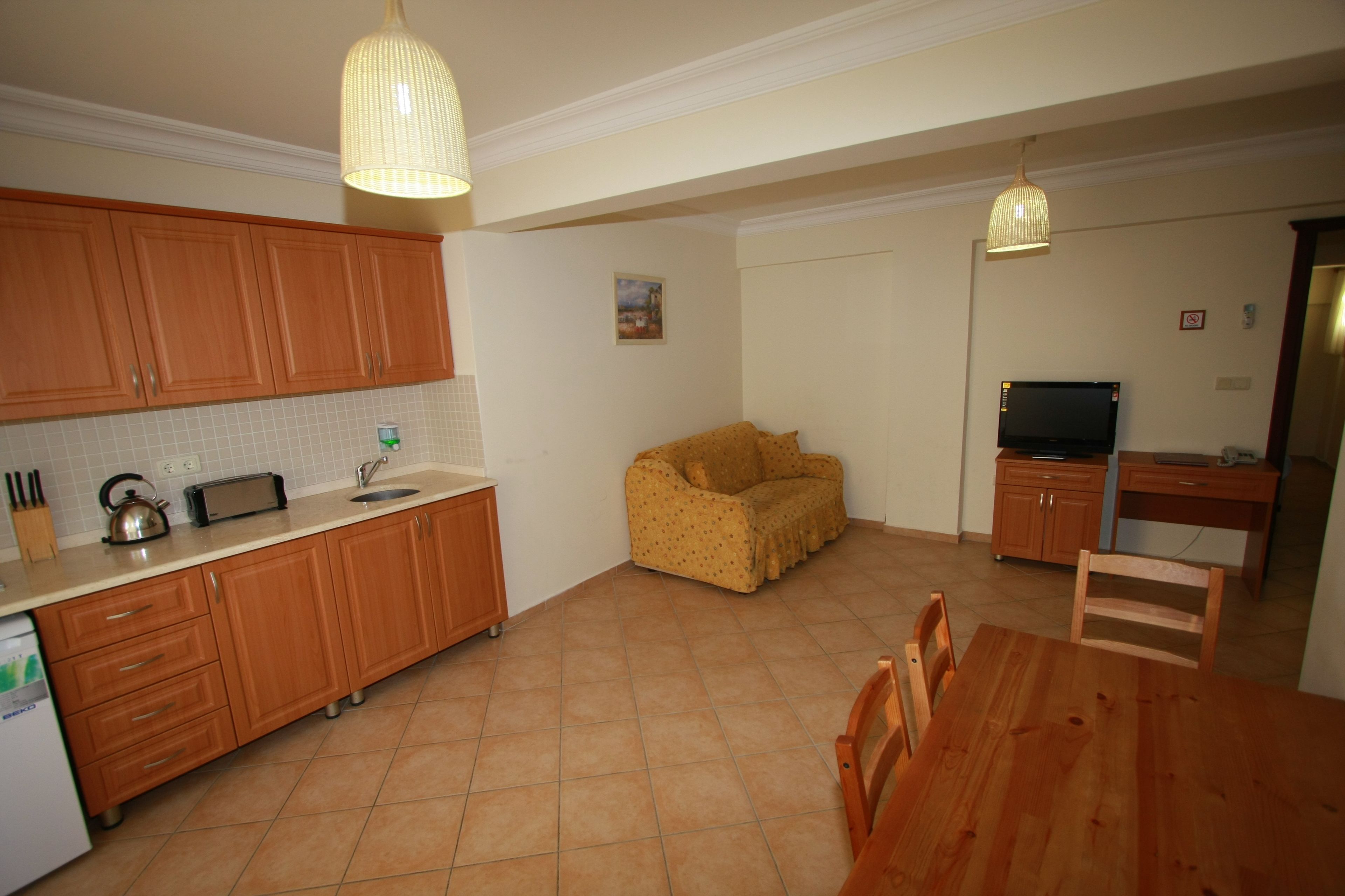 A compact kitchen with wooden cabinets, a dining table, and a sofa.
