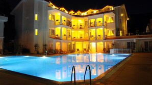 Ein mehrstöckiges Hotel mit Schwimmbad, Balkonen und Sitzgelegenheiten im Freien.