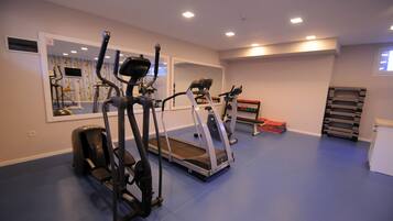 A gym with exercise equipment, a mirror, and a blue floor.