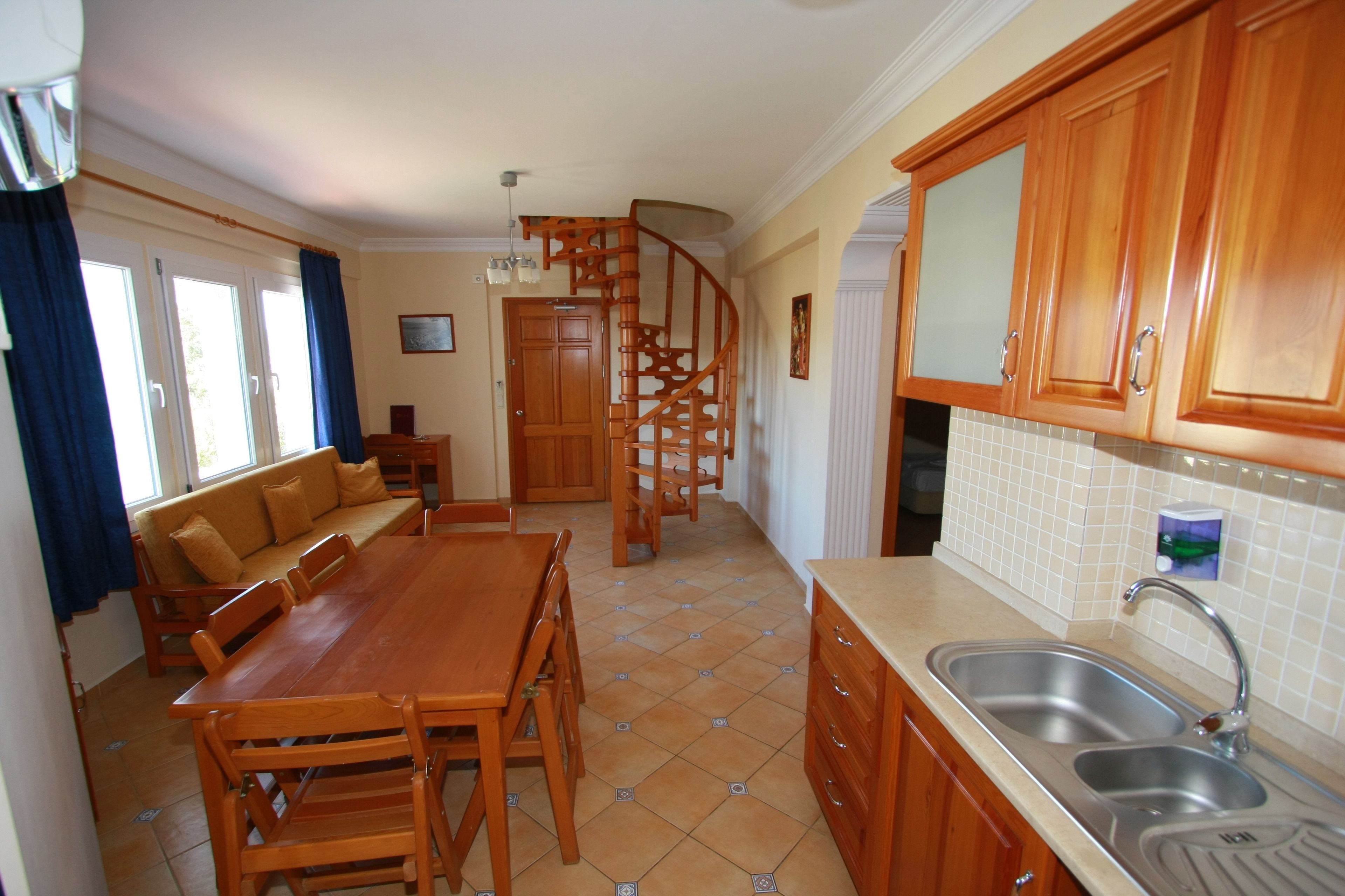 A kitchen with wooden cabinets, a dining table, and a built-in sink.