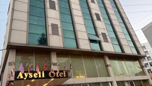 Ein mehrstöckiges Hotelgebäude mit einem auffälligen Schild, auf dem 'Aysel Otel' steht.