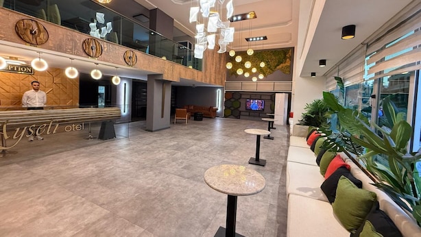 Eine moderne Hotelhalle mit Empfangstresen, Sitzbereichen und einem Fernsehbildschirm.
