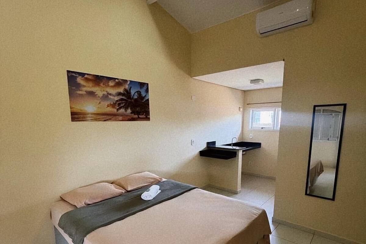Ein Schlafzimmer mit einem Bett, einem Gemälde, einem Waschbecken und einem Spiegel.
