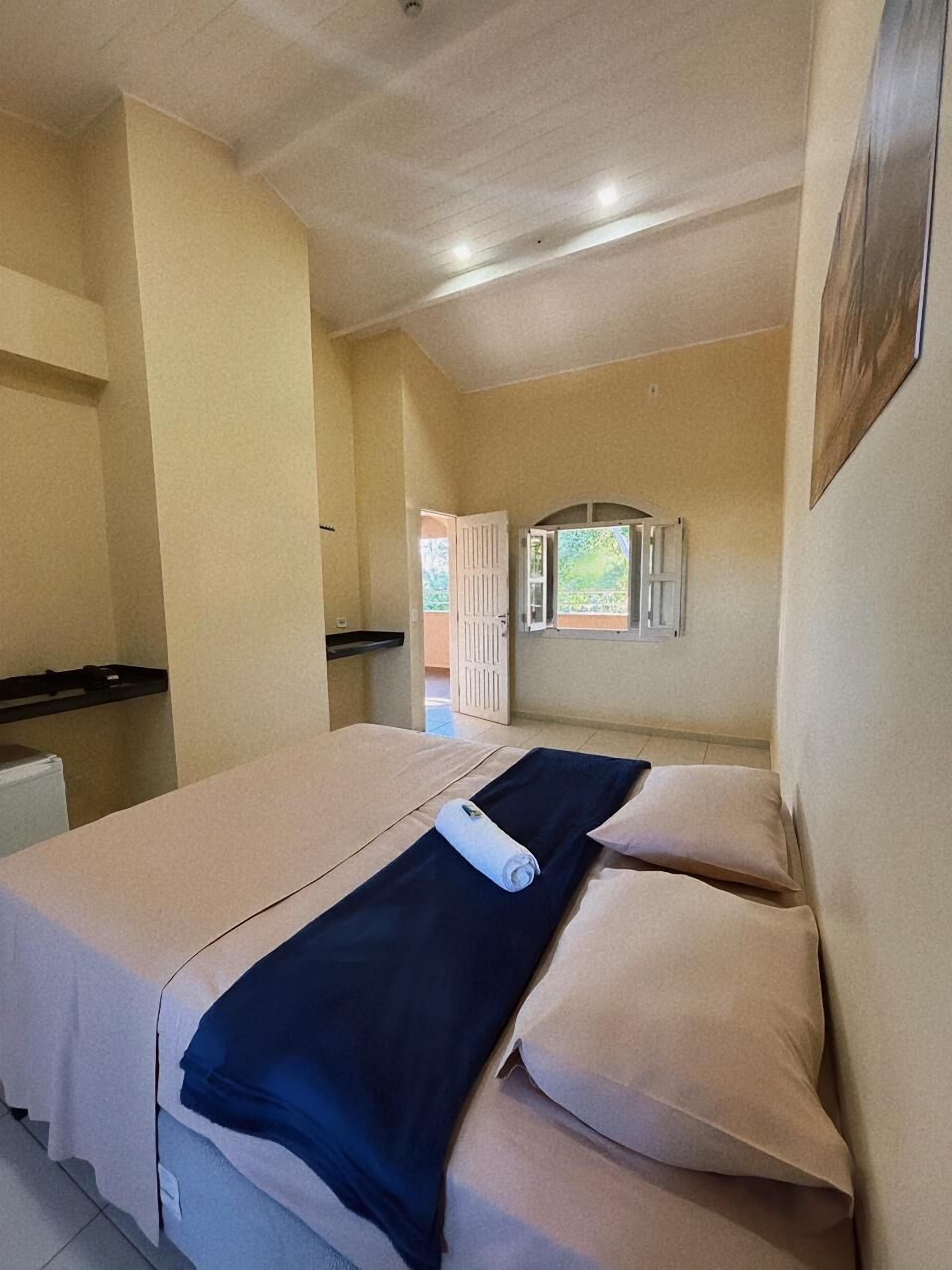 A single room with two beds, a small table, and a window with a view of the outdoors.