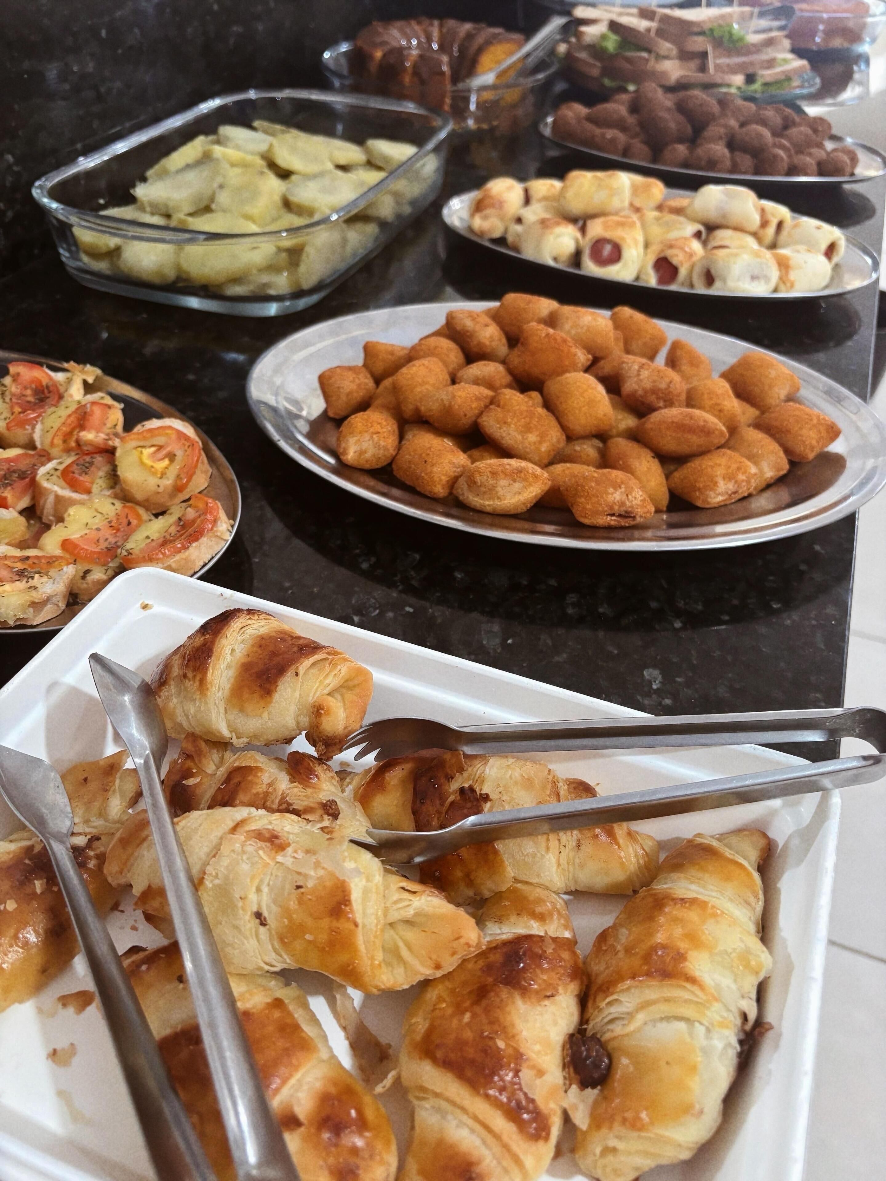Un bufé con diferentes opciones de comida, incluyendo cruasanes, panecillos y otras pastas.