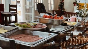 A buffet with various food items and a Christmas tree in the background. - Pousada Porto do Rio (Caraguatatuba)