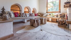 Une pièce chaleureuse avec un banc en bois, une grande fenêtre et une vue sur la verdure environnante.