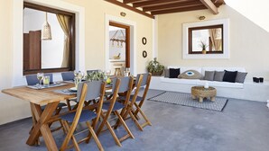 Un comedor con mesa y sillas de madera, un sofá blanco y un techo con vigas de madera.