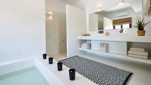 Un baño moderno con una bañera, un tapete blanco y negro estampado y tres velas encendidas.