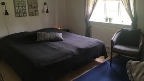 A bedroom with a large bed, a chair, a window with curtains, and motivational wall art. - Birkende Bed And Breakfast (Langeskov)