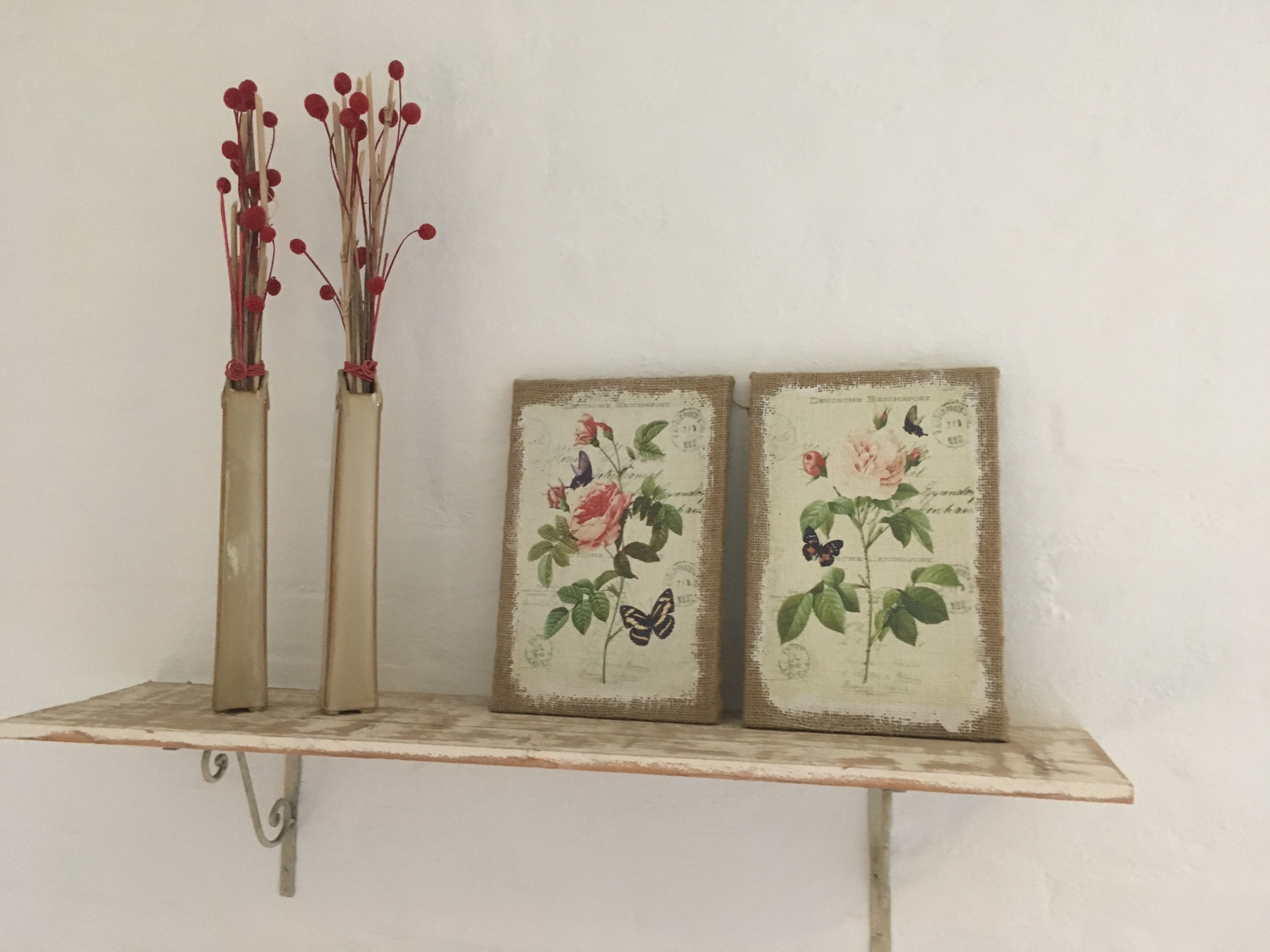 A shelf with two vases and two framed botanical prints.