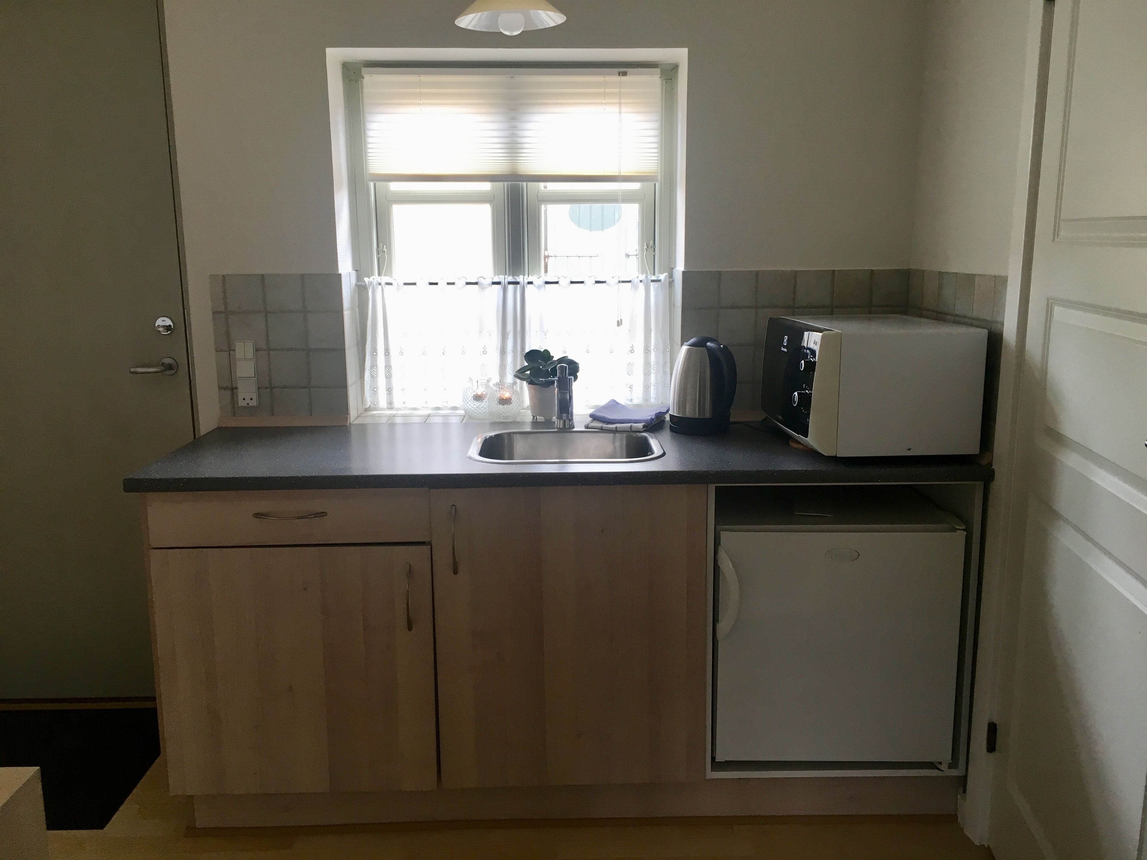 Eine kleine Küche mit Spüle, Toaster und kleinem Kühlschrank.